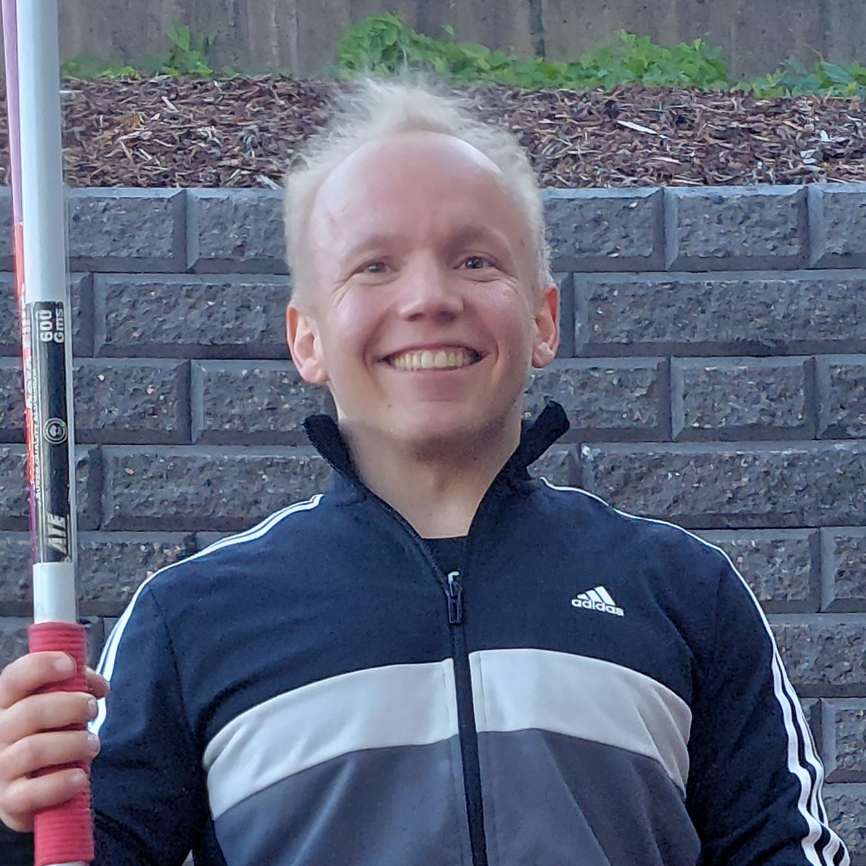 Jesse Rakkolainen hymyilemässä kameralle keihäs kädessään.